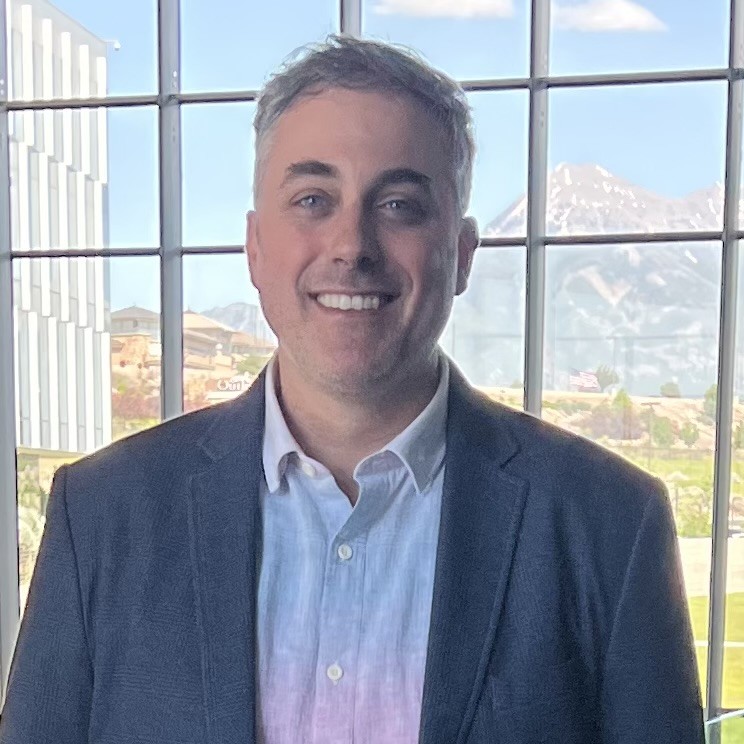 Steve Schrage smiling in a navy jacket and blue shirt